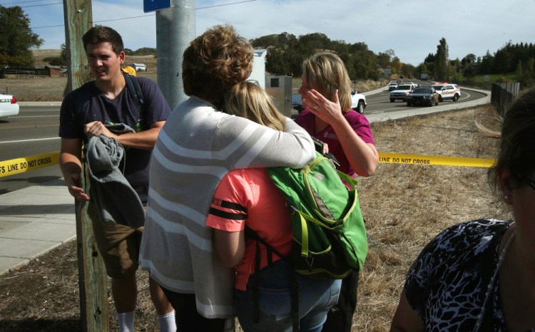 Bystanders console each other on a road leading to the Umpqua Community College campus in Roseburg, Ore. Thursday, Oct. 1, 2015, following a deadly shooting at the school.