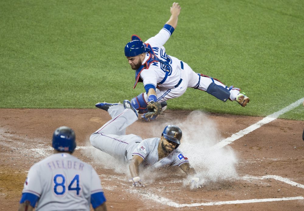 Texas’ Delino DeShields gets past Blue Jays catcher Russell Martin to score in the third inning.