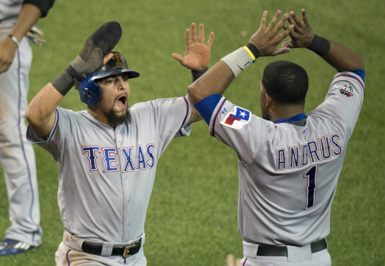 The Rangers’ Rougned Odor, left, and Elvis Andrus celebrate after Odor scored to break a 4-4 tie in the 14th inning of Friday’s American League Division Series game. The Rangers took a 2-0 lead in the best-of-five series.