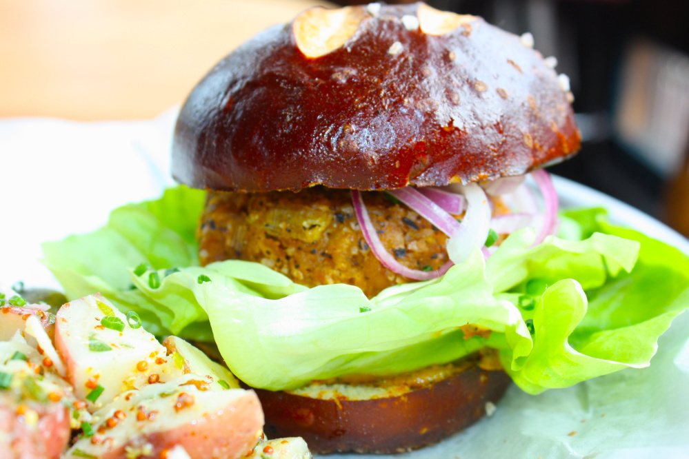 The veggie burger at LFK in Portland is made from red lentils, leeks, roasted cashews, mushrooms and panko breadcrumbs. It is served on a pretzel bun from Rosemont Bakery with a side of vegan potato salad.