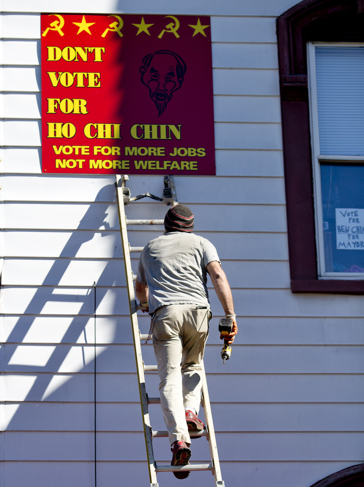 A worker for the owner of 109 Pine St. in Lewiston prepares Monday to remove a political sign containing communist symbols and a racial message. The sign refers to mayoral candidate Ben Chin, a third-generation American whose grandparents emigrated from China to the U.S.