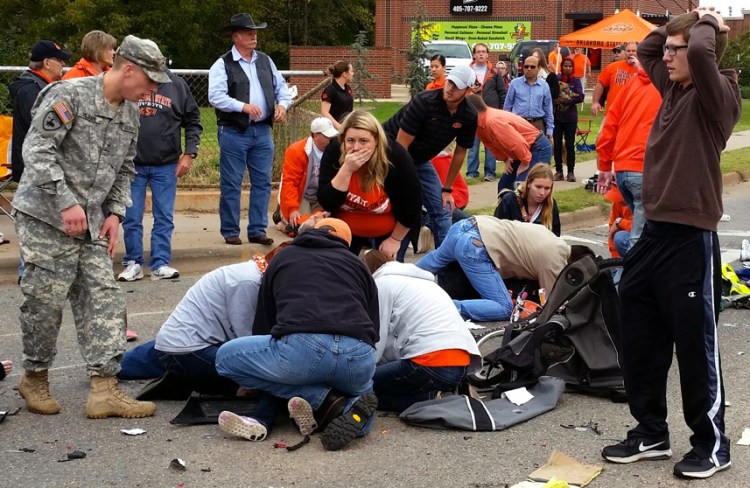 Bystanders help the injured after a vehicle crashed into a crowd of spectators during the Oklahoma State University homecoming parade, causing multiple injuries, on Saturday in Stillwater, Oka.