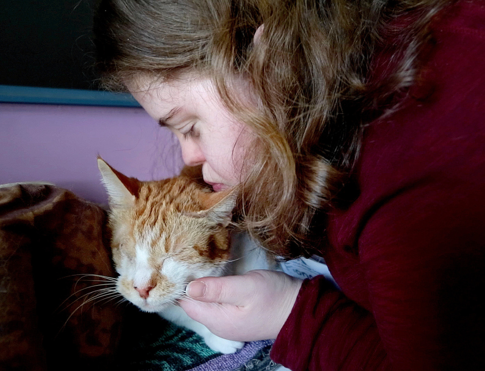 After spending an hour with two of her peers reading to cats at the Animal Refuge League of Greater Portland, Fiona Shea kisses Dylan, a one-eyed cat, goodbye. Shea is a member of STRIVE, a Portland organization dedicated to helping developmentally disabled young adults.