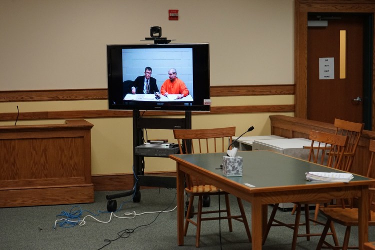 Christopher Hall, right, appears via video link from jail in Springvale District Court with defense attorney Randall Bates for Hall's initial appearance on assault charges in connection with an attack on a lawyer using a cane equipped with a shocking device.