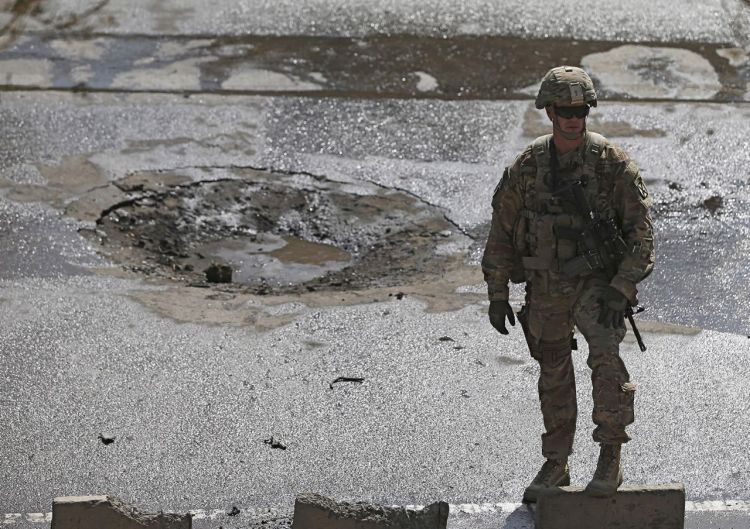 A soldier stands at the site of a suicide car bomb blast in Kabul on Sunday. A suicide car bomber targeted a convoy of troops in the Afghan capital during rush-hour traffic, flipping an armored vehicle on its side, but the number of casualties was unknown. Reuters
