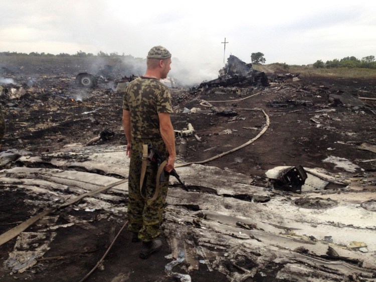 An armed pro-Russian separatist stands at a site of a Malaysia Airlines Boeing 777 plane crash in the settlement of Grabovo in the Donetsk region Thursday. Dozens of bodies were scattered around the smoldering wreckage. An emergency services rescue worker said at least 100 bodies had so far been found at the scene. Reuters