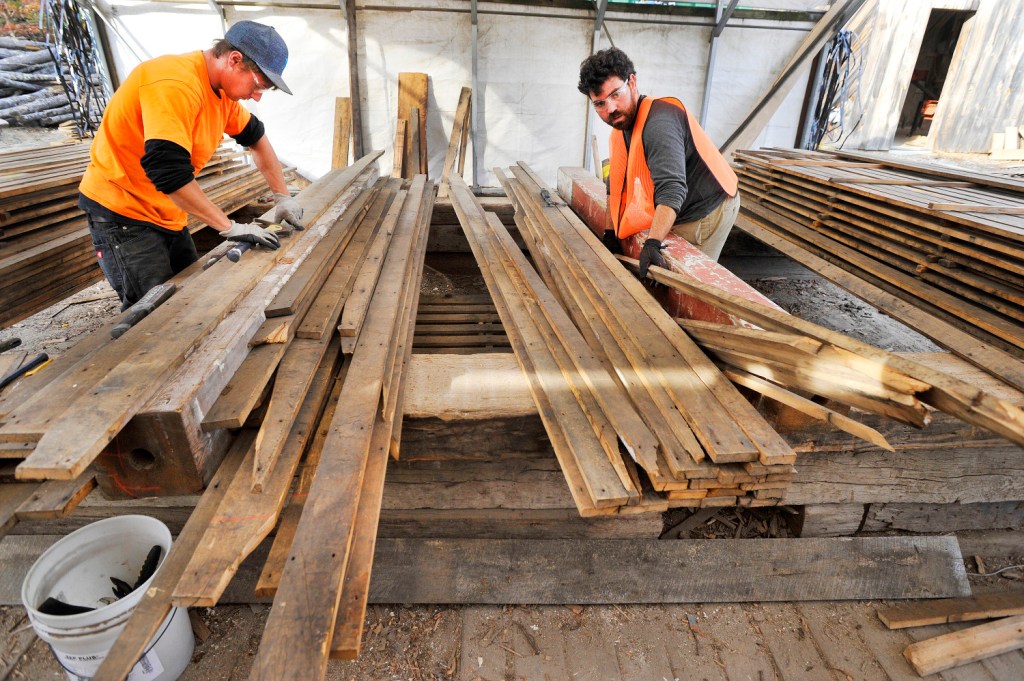 In this 2015 file photo, Travis Dame, left, of North Berwick, and Aaron Corme of Somersworth, New Hampshire, remove nails from newly acquired boards at Longleaf Lumber in Berwick. The company has supplied reclaimed wood from Maine for several Boston restaurants.