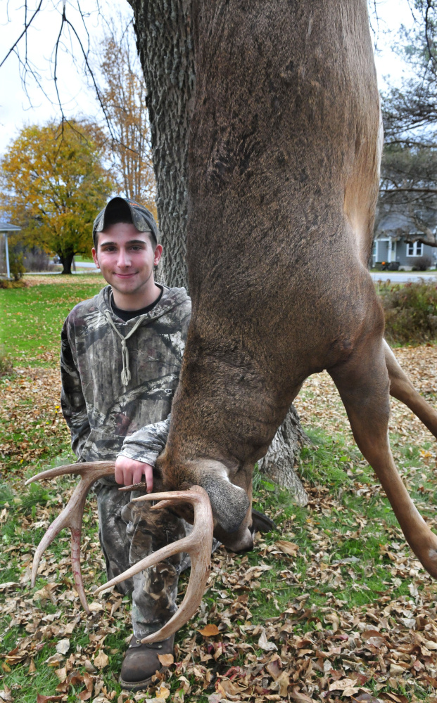 Izaac Hatt, 16, holds the 217-pound, eight-point buck he bagged on Saturday, opening day of firearm deer season for Maine residents.