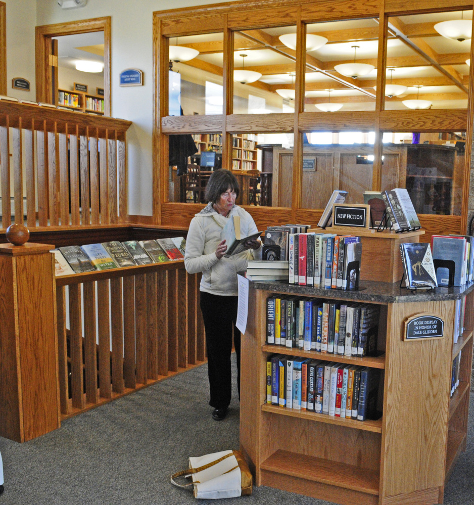 Gale Ramsey browses a shelf of new books just inside the door on Friday at C.M. Bailey Public Library in Winthrop.
