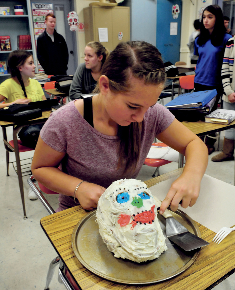Winslow Junior High School student Savannah Joler begin to cut a cake made in the form of a skull during the Day of the Dead celebration on Monday.