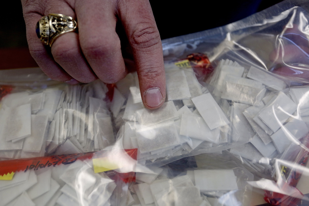 Scott Pelletier of the Maine Drug Enforcement Agency shows heroin packets the agency seized Tuesday, Feb. 11, 2014.