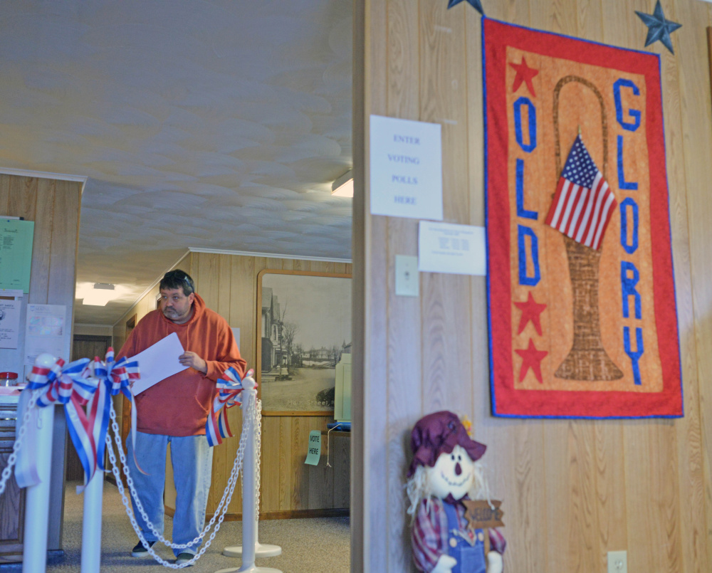 A voter leaves the polls with his ballot after voting at the Anson Town Office on Tuesday.