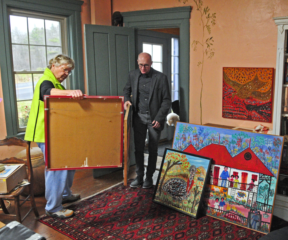 Barbara Skapa, left, and Kent Shankle, executive director of the Waterloo Center For The Arts, look at Haitian paintings on Friday at Skapa’s Mount Vernon home. Skapa collected several paintings by Gerard Fortune when she worked in Haiti.