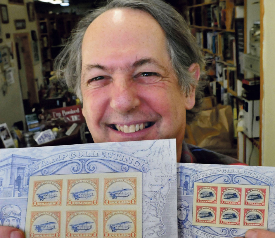 Robert Sezak holds copies of two versions of postage stamps on Monday. The copies at left show a Jenny aircraft in the upright flying position that could fetch $50,000 when auctioned at Julia”s Auctions in Fairfield this February.