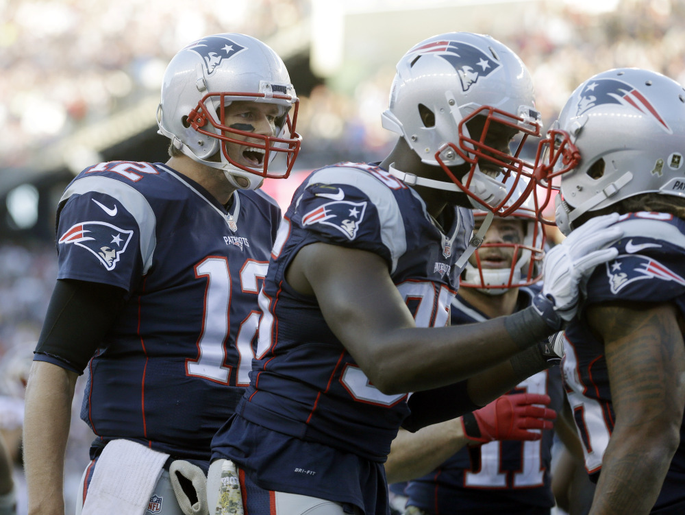 New England Patriots quarterback Tom Brady, left, and defensive end Chandler Jones, center, congratulate running back Brandon Bolden, right, after his touchdown against Washington on Sunday in Foxborough, Mass.