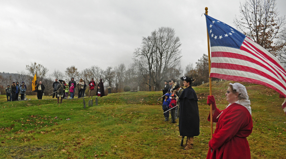 An American flag with 13 stars flies as Cub Scout Pack 684 joins re-enactors at the grave of Revolutionary War soldier Capt. Daniel Savage in Riverside Cemetery during a Veterans Day event on Wednesday in Augusta.