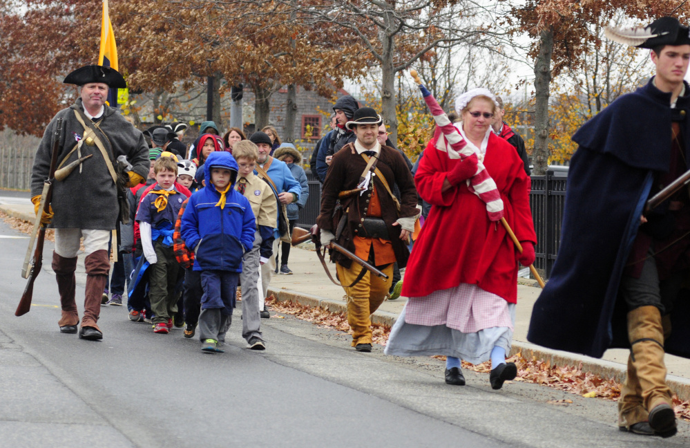 Cub Scout Pack 684 joins re-enactors marching from Old Fort Western to Riverside Cemetery during a Veterans Day event on Wednesday in Augusta.