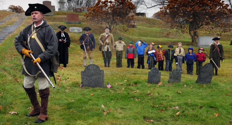 Pete Morrissey, left, speaks to spectators as Cub Scout Pack 684 joins re-enactors at the grave of Revolutionary War soldier Capt. Daniel Savage in Riverside Cemetery during a Veterans Day event on Wednesday in Augusta.