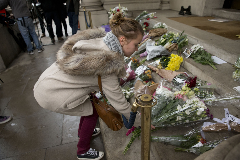A woman lays flowers for the victims of the deadly attacks in Paris, outside the French embassy in London, on Saturday. French President Francois Hollande said more than 120 people died Friday night in shootings at Paris cafes, suicide bombings near France’s national stadium and a hostage-taking slaughter inside a concert hall.