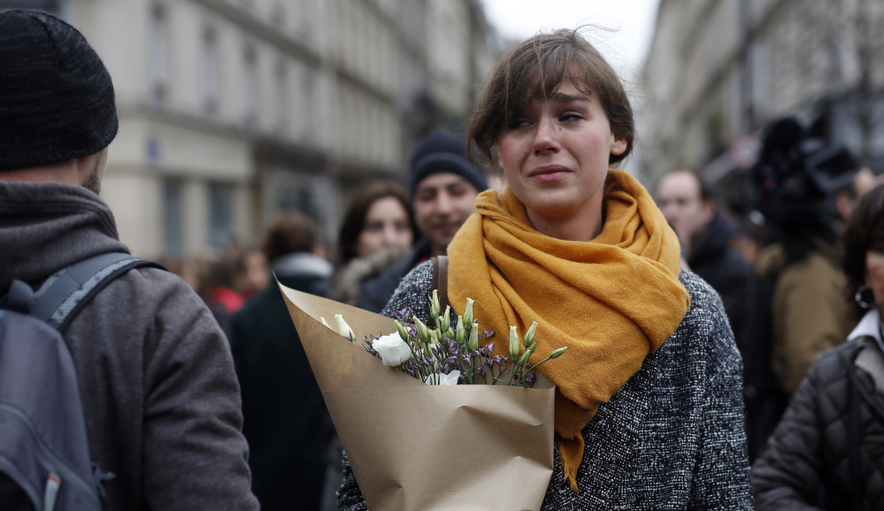 A woman carries flowers in Paris on Saturday. A California college who was spending a semester abroad was the sole American among the dead.