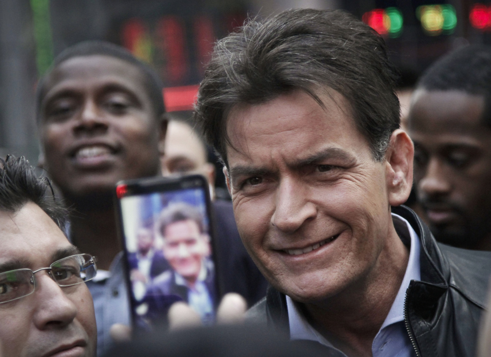 In this Monday, Jan. 14, 2013, file photo, actor Charlie Sheen is mobbed for autographs and photos as he makes his way through Times Square in New York.