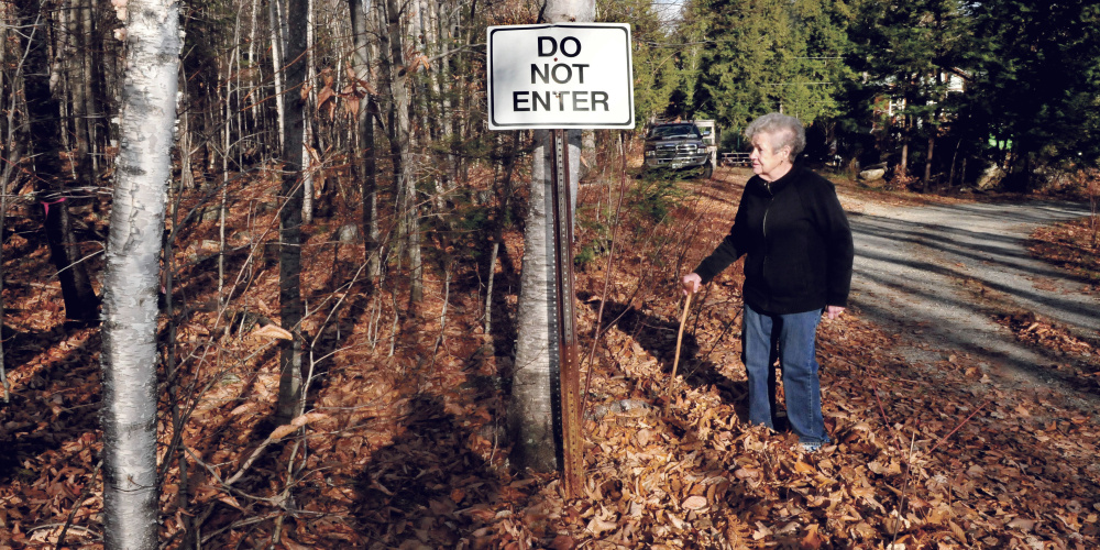 Doris Jorgensen stands beside the sign near her home on Long Pond and property where a proposed summer camp may be built off Jorgensen Estate Road in Rome on Monday.