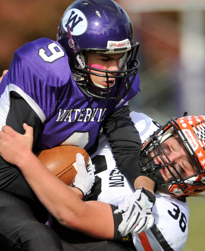 Waterville’s Demetrius Ramirez (9) is tackled by Winslow’s Kenny Rickard during a Big Ten Conference game at Drummond Field in Waterville.