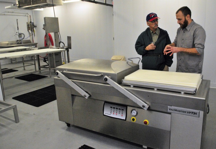 City councilor Phil Hart, left, talks about a cryovac packaging machine with Eben Harrington, the hazard analysis and critical control points manager, during a tour of Central Maine Meats processing facility in Gardiner on Thursday.