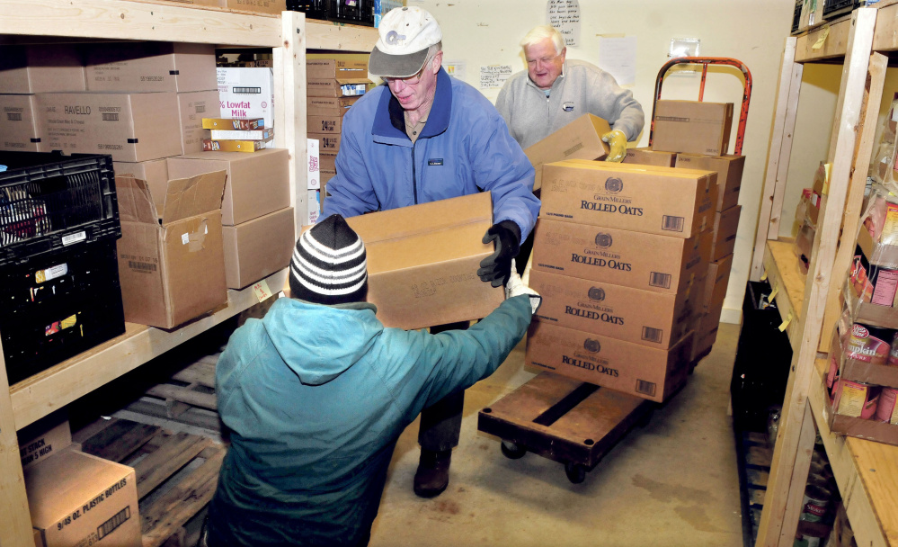 These volunteers load food onto shelves at the Care and Share Food Closet in Farmington on Wednesday. From left are Carl Hutchinson, Dave Scribner and board member Dana Bullen.