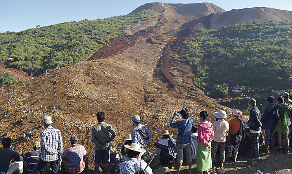 People look over an area covered by a landslide at Phakant jade mine in Kachin State, Myanmar, on Saturday. The landslide near the jade mine in northern Myanmar killed about 100 people and left many missing.