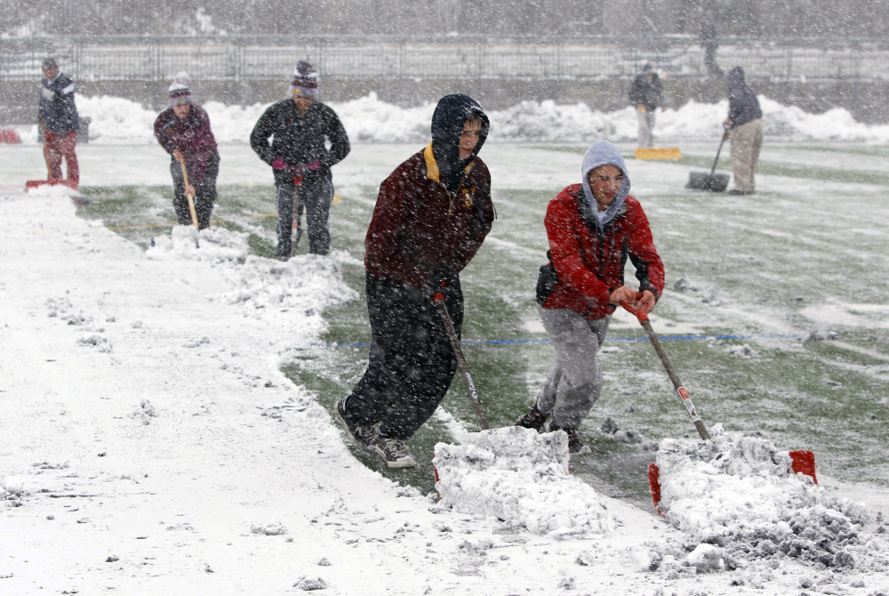 Crews at Montini High School work to remove snow from the field before the Class 6A semifinal high school football game against Prairie Ridge in Lombard, Illinois, on Saturday.