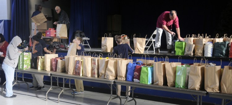Students and volunteers hand out the ingredients for Thanksgiving dinner Monday in the gymnasium at St. Michael School in Augusta.