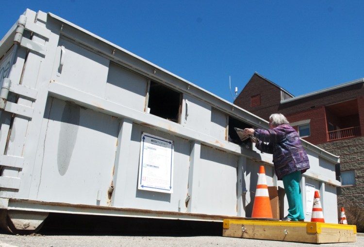 Laurie Southard tosses her recyclables into the container in May in the back lot of City Center in Augusta. City council may consider adding another recycling location on the city’s west side.