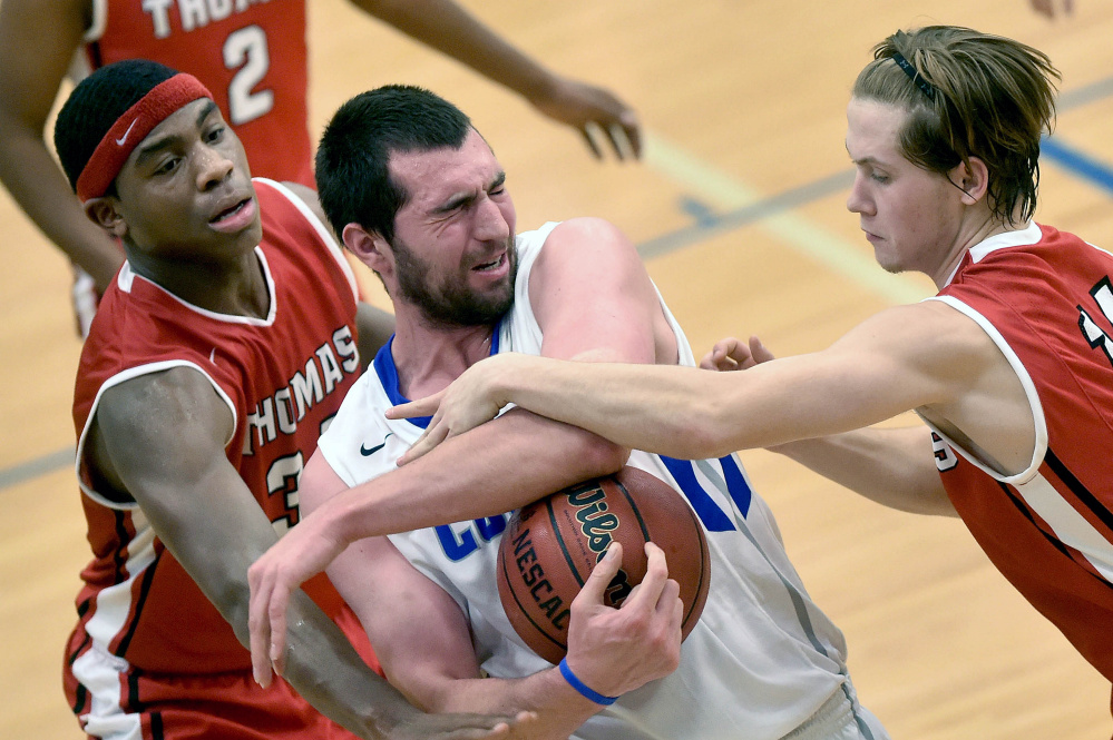 Thomas College’s Dayne Savage, right, fouls Colby College’s Chris Hudnut, middle, as Thomas’ Carlos Gonzalez helps defend during a non-conference game Wednesday.
