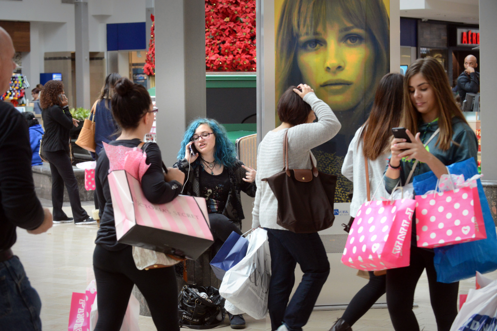 Bree Stopper, middle, talks on the phone after finishing work at a clothing store in the Willowbrook Mall, on Friday as people shop on Black Friday in Wayne, New Jersey.
