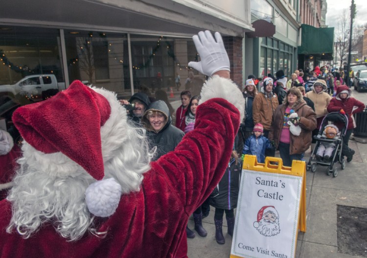 After arriving by horse-drawn wagon, Santa Claus waves to people waiting in line outside his castle during The Riverfront Holiday event on Saturday in downtown Augusta.