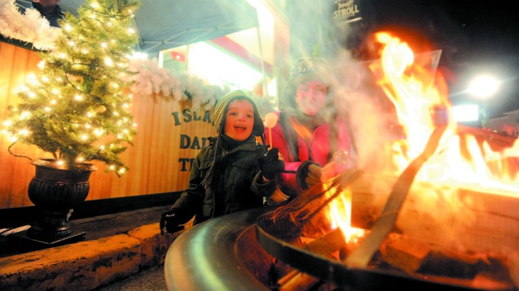 Christina Easler, right, and her son Gavyn, 4, enjoy a hot marshmellow over an open fire on Water Street at the 2013 Holiday Stroll in Skowhegan. This year’s kicks off Friday.