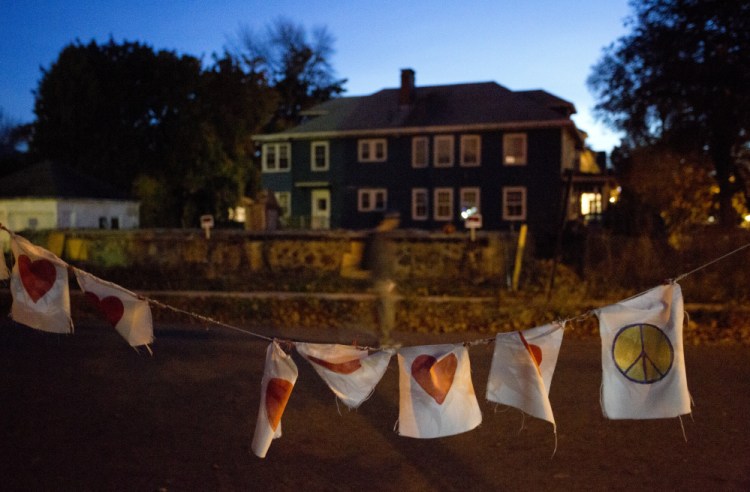 A string of flags with hearts and peace signs serves as a memorial as emotions still run strong a year after a fire on Portland’s Noyes Street killed six people in their 20s.