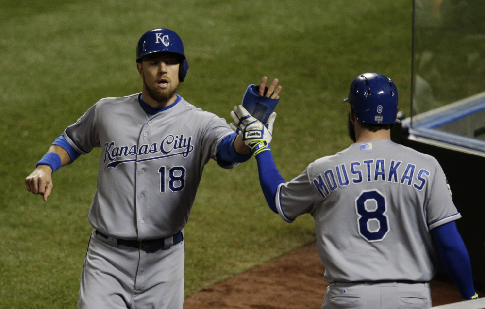 Kansas City’s Ben Zobrist is congratulated by Mike Moustakas after scoring on a single by Lorenzo Cain in the sixth inning. Zobrist also scored the tying run in the eighth, and Moustakas drove in the go-ahead run.