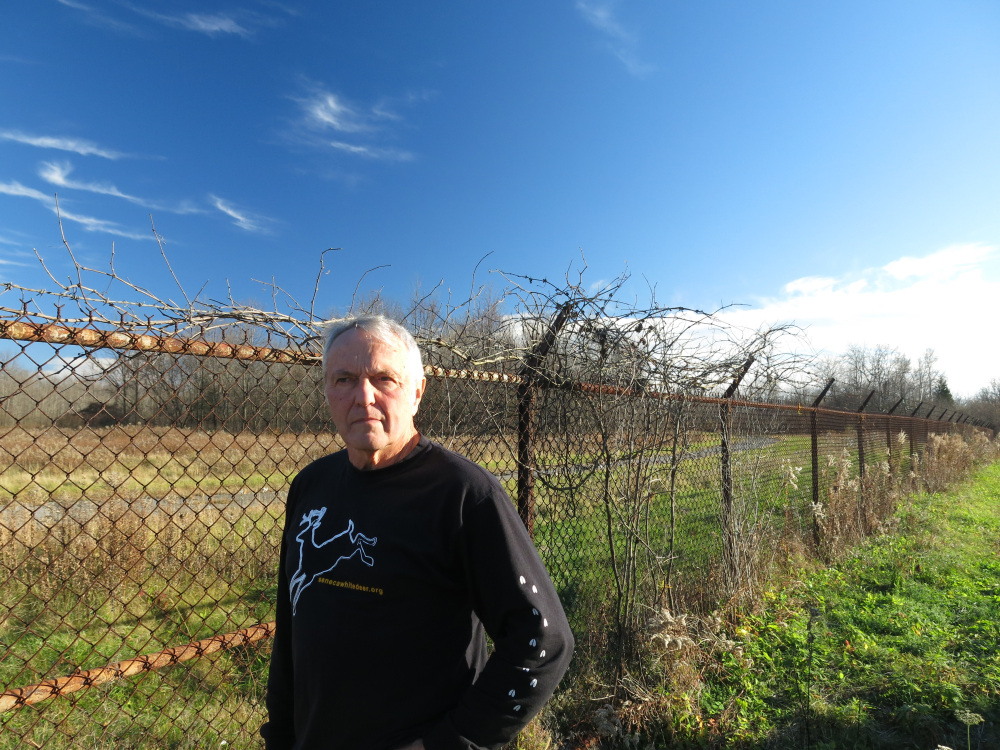 Dennis Money, president of Seneca White Deer Inc., stands beside the perimeter fence of the former Seneca Army Depot in Romulus, N.Y.. The weapons storage site is up for sale and Money hopes to buy all or part of the land in partnership with The Nature Conservancy to save the hundreds of rare white deer there. The Associated Press