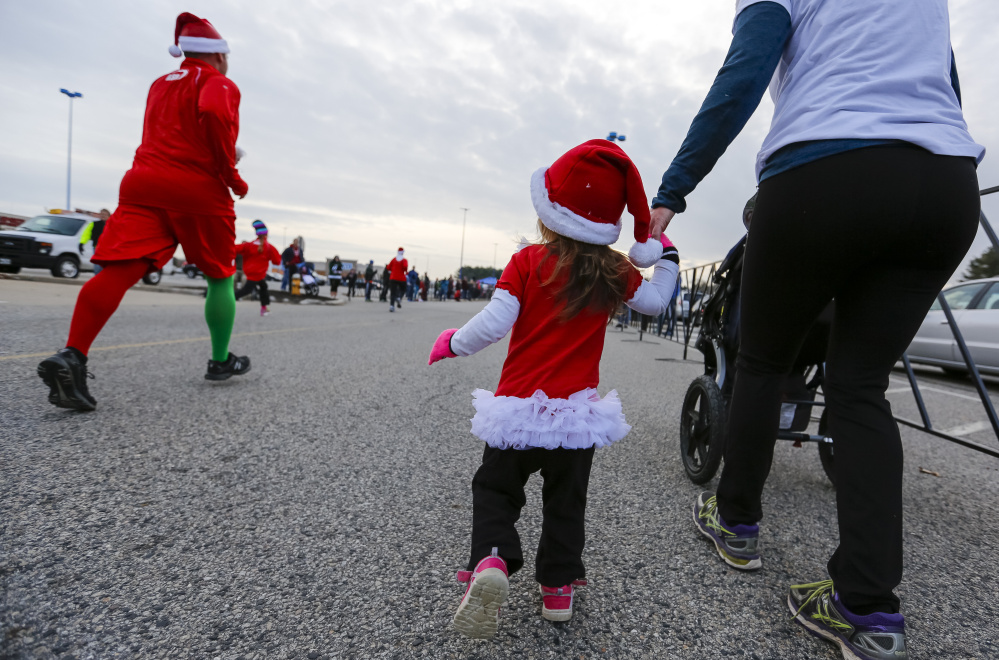 Evelyn Scherb, 2, of South Portland, holds her mother’s hand near the finish line for the annual Santa Hustle Half Marathon and 5K on Sunday at the Maine Mall. Jessica Scherb said her daughter walked the last quarter mile of the 5K, but rode in a stroller for most of the way.