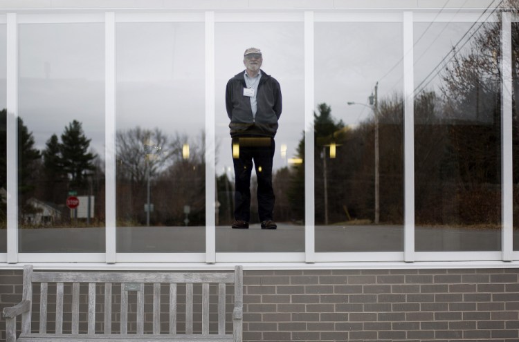 David Clark poses on a road in Augusta, with the image superimposed on a window at the Harold Alfond Center for Cancer Care, where his late wife was treated for the disease. Since then, Clark has logged about 30,000 miles driving cancer patients to their appointments.
Gabe Souza/Staff Photographer