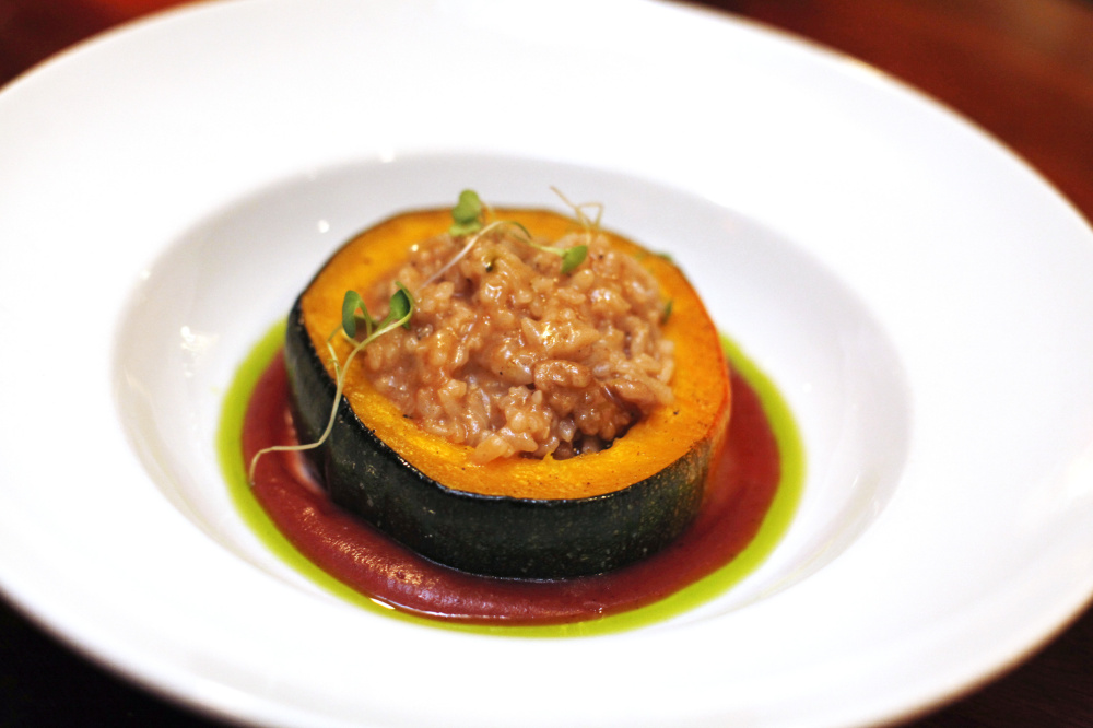 Walnut risotto-stuffed long pie pumpkin with savory cranberry apple puree and herb oil.