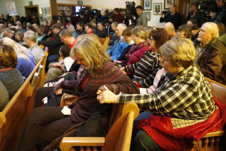 Women hold hands during a vigil in a church to mark Friday’s shooting at a Planned Parenthood clinic Saturday in Colorado Springs, Colorado.