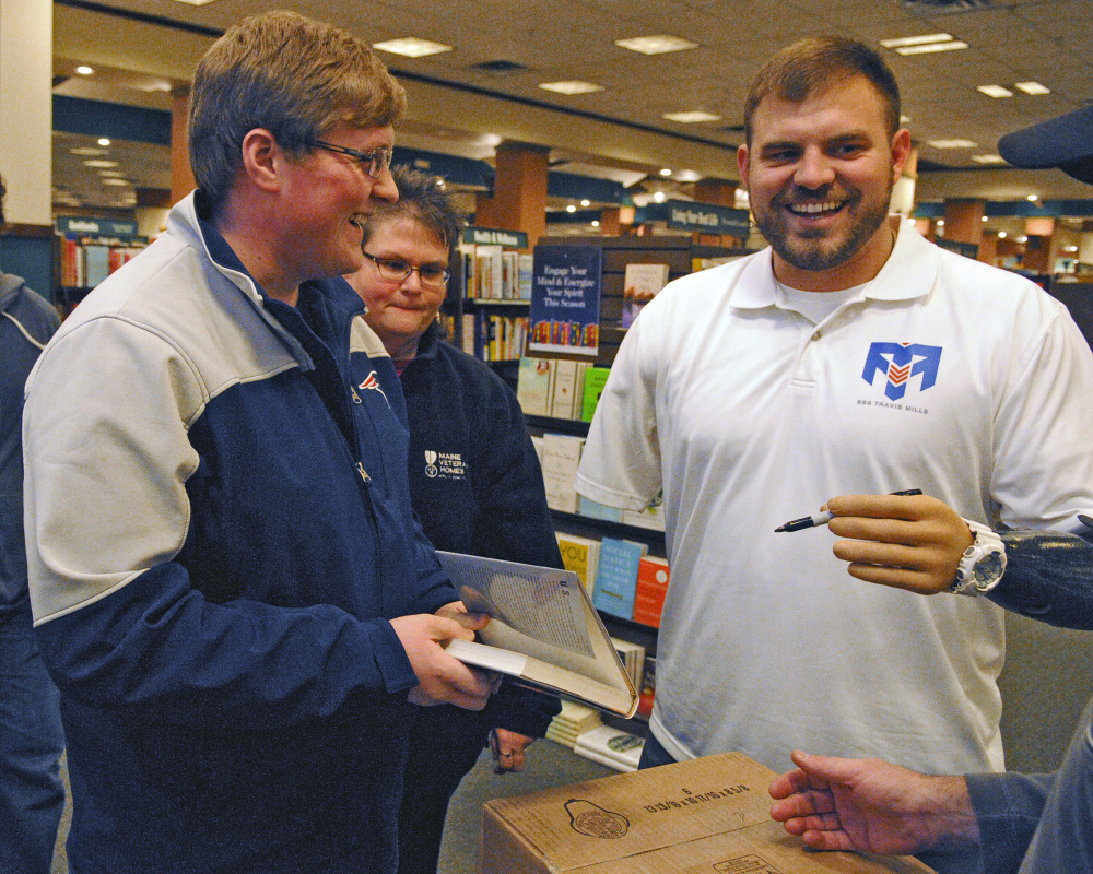 Travis Mills, right, jokes around with customers while autographing a copy of his book “Tough As They Come” on Tuesday at the Barnes and Noble store in Augusta.