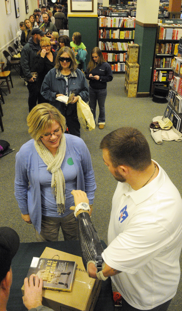 Travis Mills, right, jokes with a customer while demonstrating the rotating wrist on his prosthetic arm Tuesday at a book signing where he autographed copies of his autobiography, “Tough As They Come,” at the Barnes & Noble bookstore in Augusta.