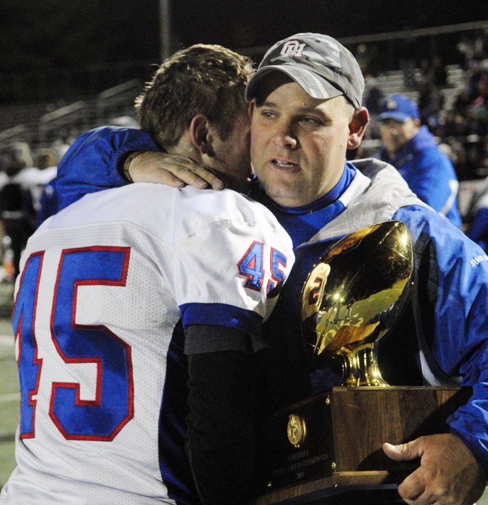 Kyle Tervo hugs Oak Hill coach Stacen Doucette after the Raiders beat MCI 41-21 to win the 2014 Class D state title.