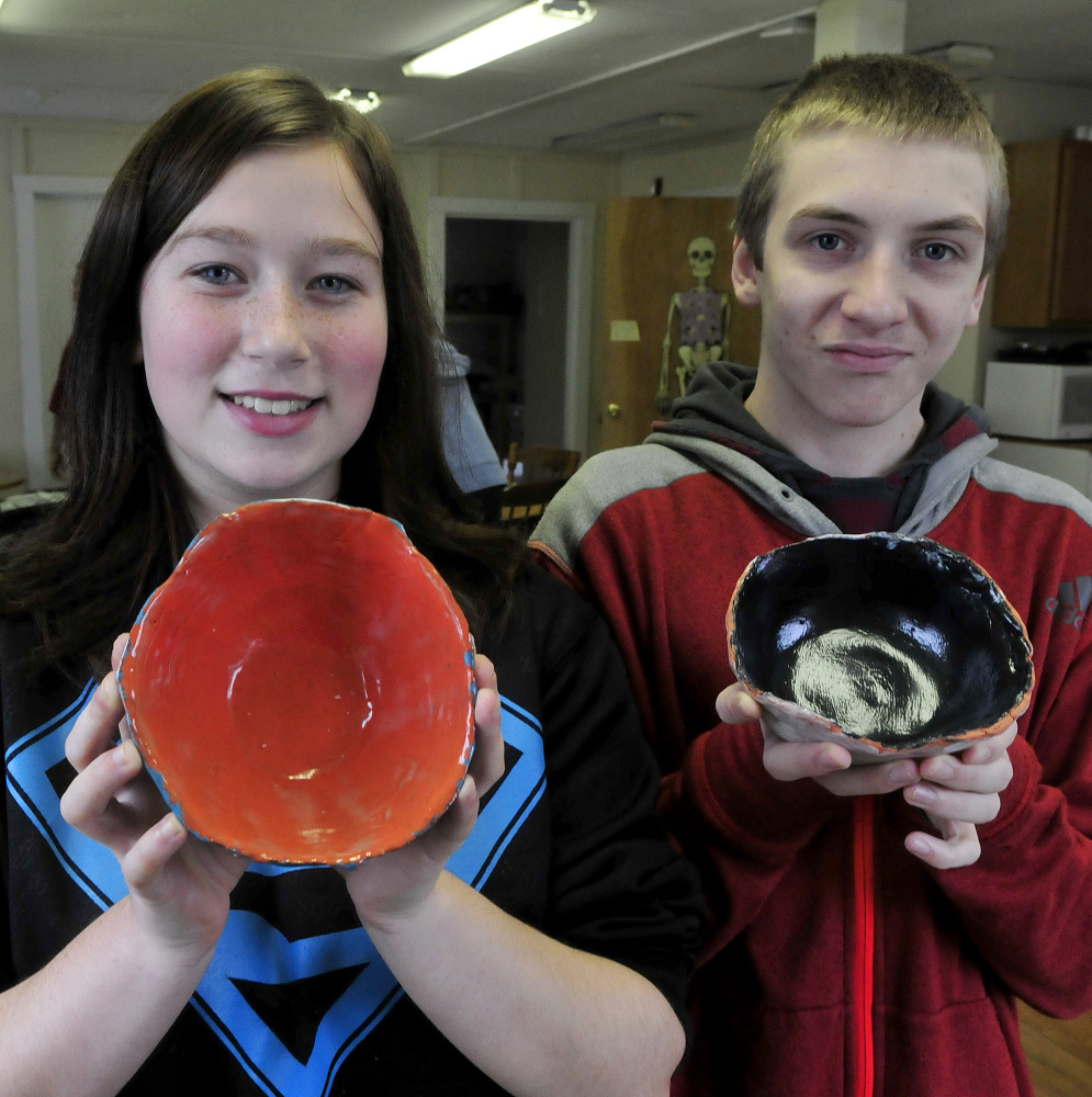 Skowhegan Area Middle School students Crystal Harris and Gavin Hessert hold handmade bowls that will be part of the Empty Bowls project fundraiser for area soup kitchens during this weekend Holiday Stroll event in Skowhegan.