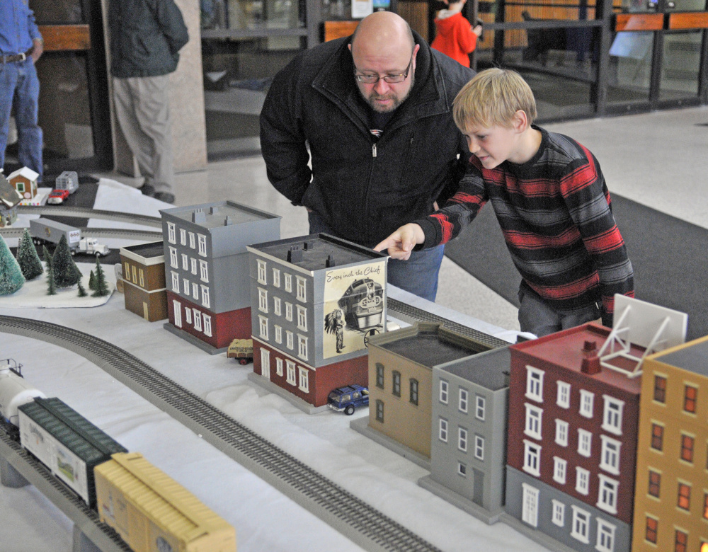 Sean Boynton, left, and his son Sam Boynton, 11, of China, look at the model railroad displays on Friday in the atrium of Maine Cultural Building, which houses the Maine State Museum, in Augusta.