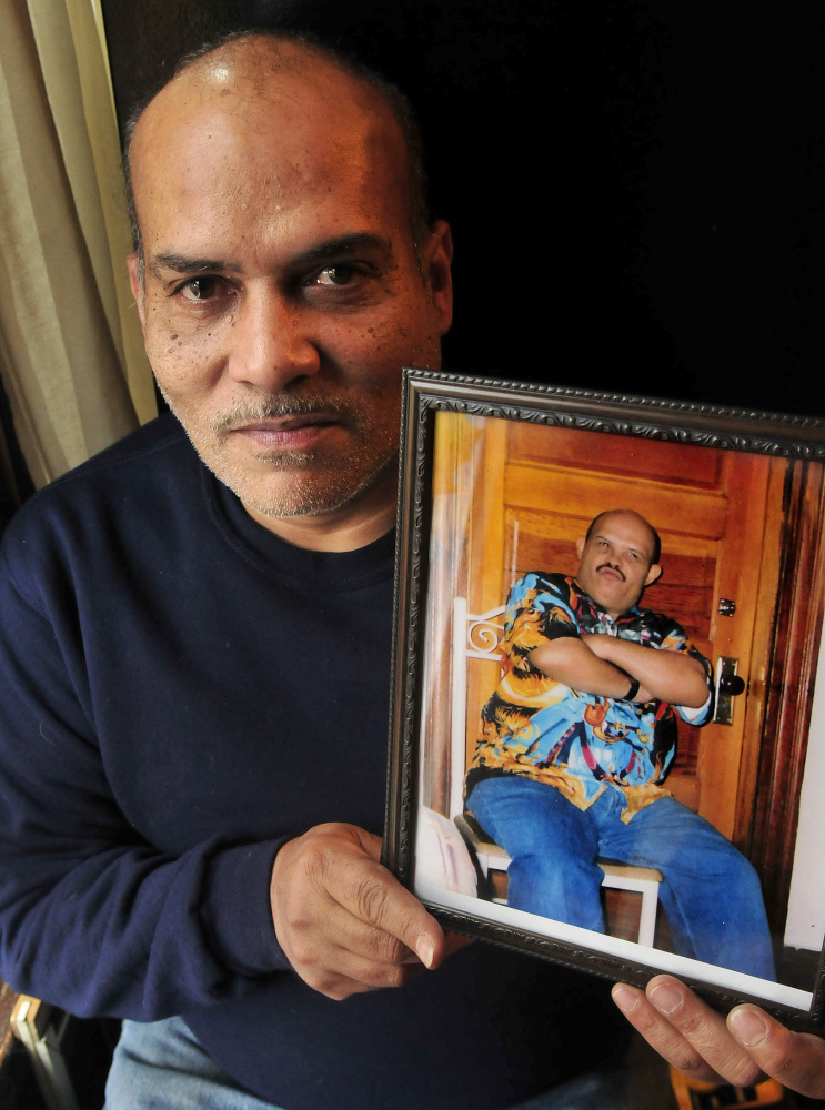 Florentino Santiago holds a photograph of one of his deceased brothers, Jesus, on Thursday at his apartment in Winslow.